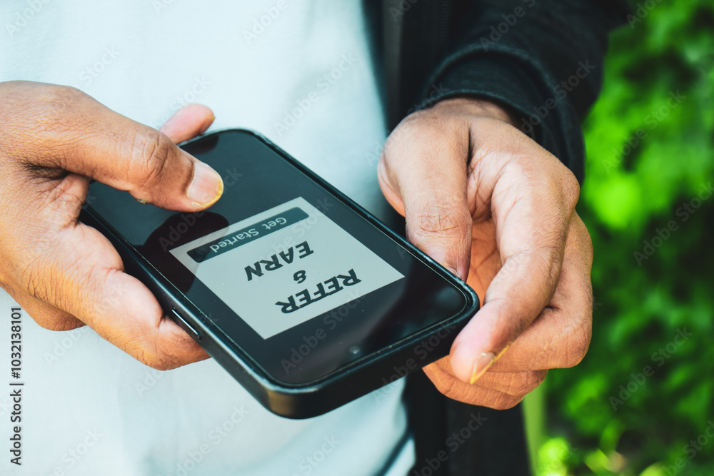 Ophthalmology Associates, S.C. - Person holding a smartphone displaying 'Refer & Earn Get Started'